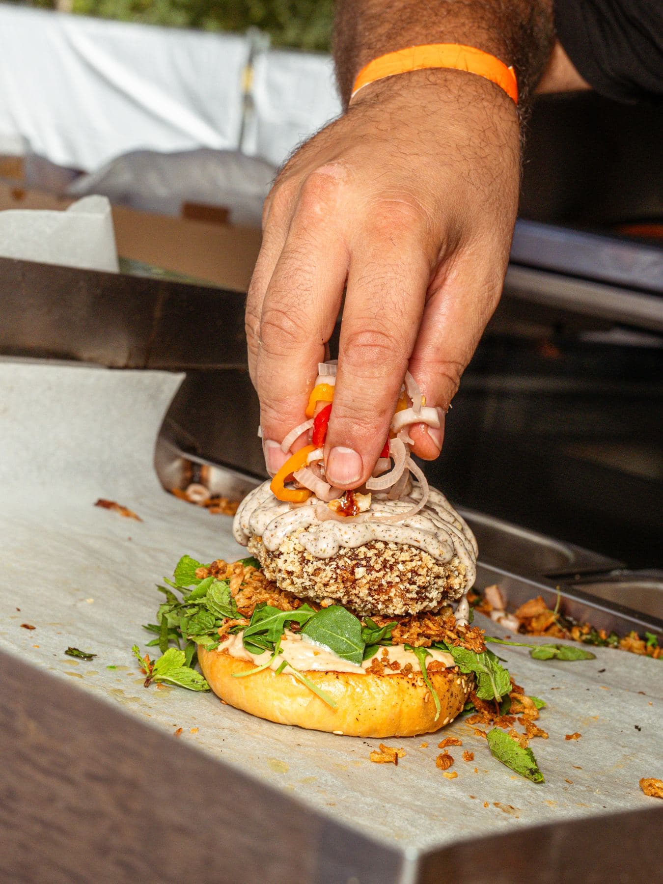 Una mano termina una hamburguesa sobre la encimera de acero inoxidable de un remolque food truck