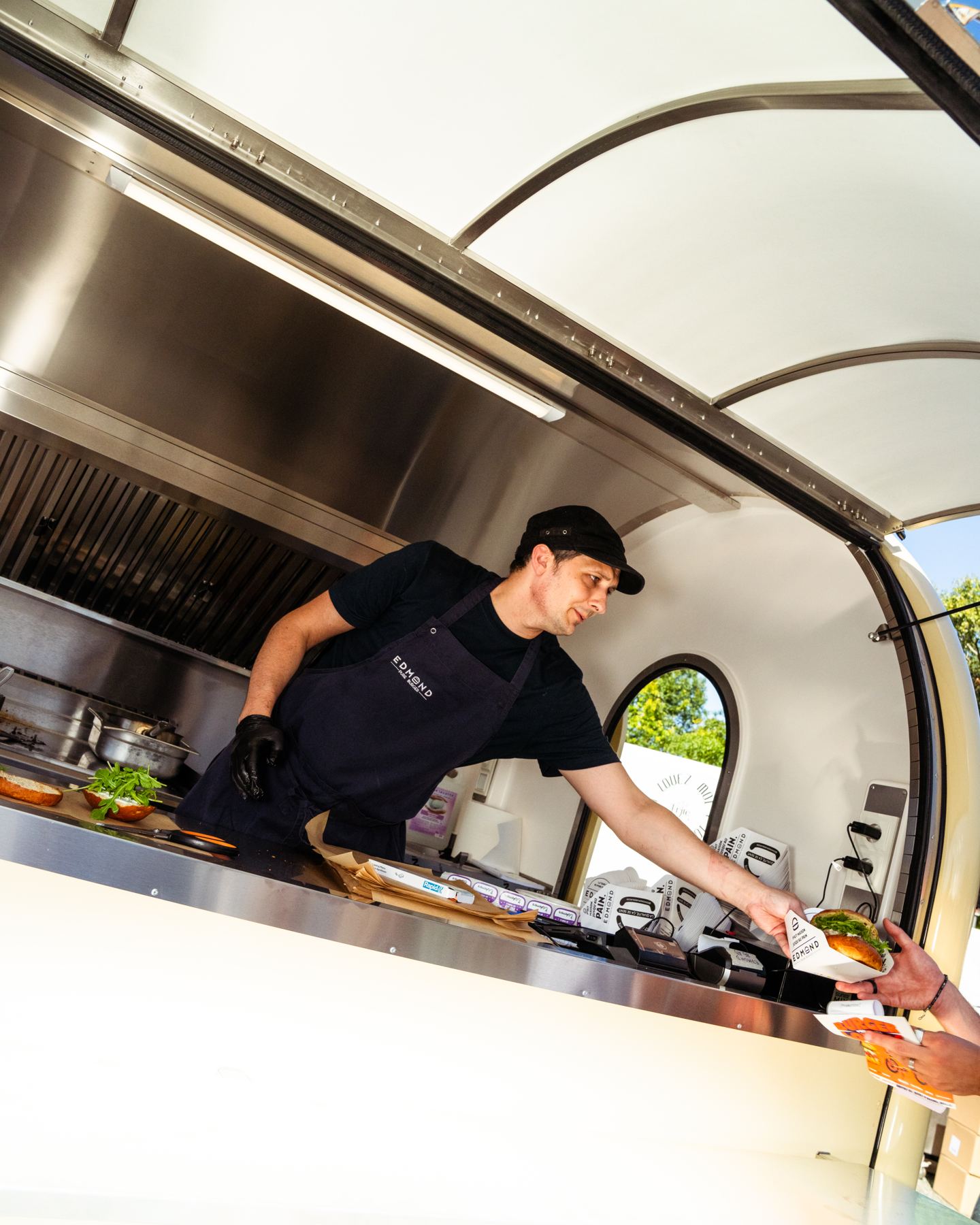 Un cocinero atiende a un cliente desde su remolque food truck