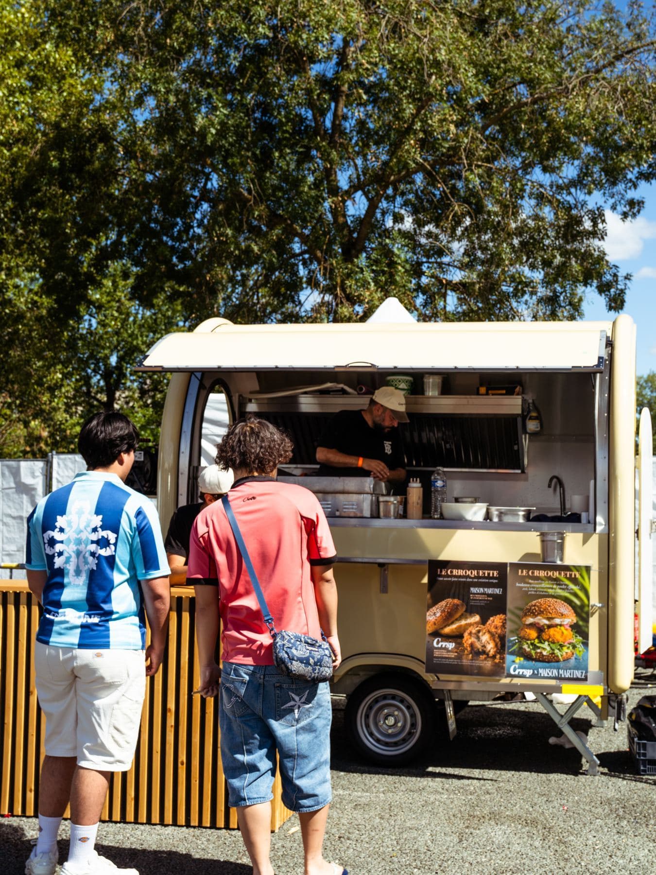 Remolque de venta ambulante beige a pleno rendimiento, con clientes en el mostrador