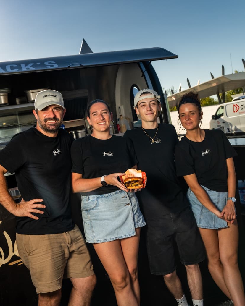 El equipo de Jack’s Burger delante de su remolque food truck, con una hamburguesa en la mano
